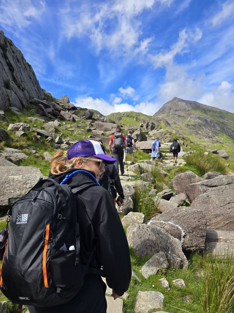 Hikers climbing a rocky path on Snowdon under blue skies
