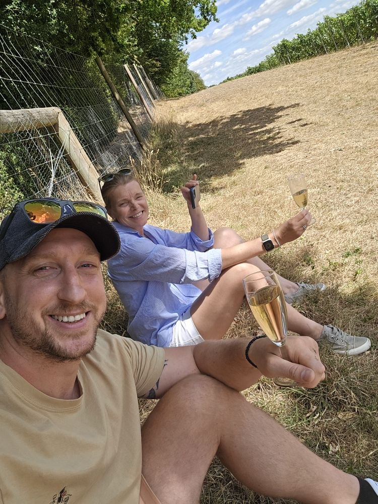 Two guests relaxing on the grass with sparkling wine at a vineyard